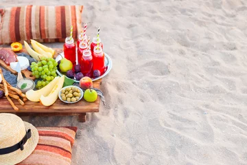 Photo sur Plexiglas Pique-nique Picnic on the beach at sunset in the style of boho. Concept outdoors evening healthy dinnner with fruit and juice