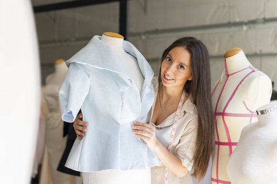 Young fashion designer fitting clothes on dressmaker's model