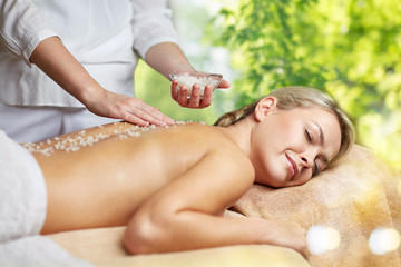 Fototapeta na wymiar beauty, wellness and relaxation concept - beautiful young woman lying having salt massage in spa over green natural background