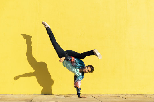 Acrobat doing movement training in front of yellow wall