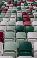 Empty tribunes of a modern stadium with nubers without spectators and colored chairs in the center of the arena