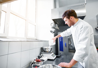 cooking food, baking and people concept - happy male chef cook with eggs pouring flour into bowl on scale at restaurant or bakery kitchen