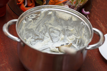 Dirty metal pot with white sauce.