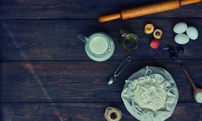 Baking background with copy space. Cooking ingredients for dough and pastry, eggs, flour and butter on dark rustic wood. Homemade baking theme. Top view, mockup for menu, recipe for culinary classes.