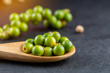 Black pepper spice peppercorn on wooden spoon and dark rustic background