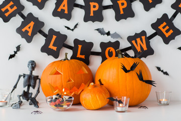 holidays and decoration concept - jack-o-lantern or carved pumpkins with candies and happy...