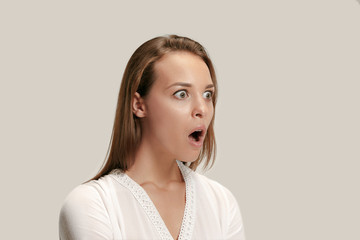 Wow. Beautiful female half-length front portrait isolated on gray studio backgroud. Young emotional...