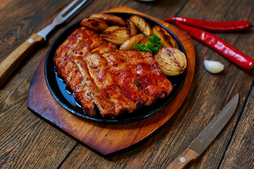On the table is a cast-iron pan with delicious meat roasted until golden brown, cutlery with wooden handles lie close