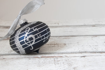 black christmas ball with clef of notes on white wooden background