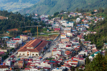 Aerial view of clusters of buildings nestled in the green valley of Sapa, Vietnam