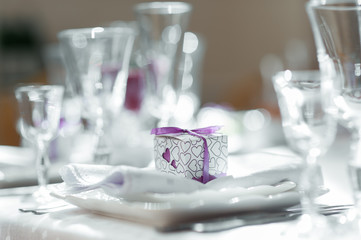white box with a purple ribbon with a gift for guests on a table with dishes cooked for food