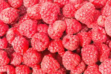 Heap of ripe juicy raspberries in wicker market box