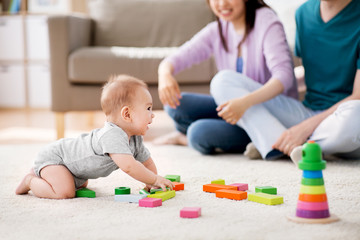 family, parenthood and people concept - happy mother, father and baby boy playing toy blocks at home