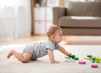 Naklejka premium babyhood, childhood and people concept - little asian baby boy playing with toy blocks at home