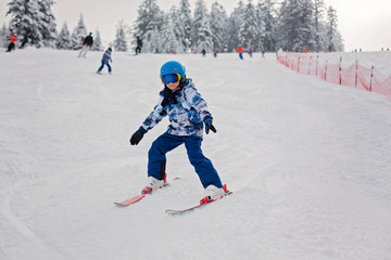 Fototapeta na wymiar Cute preschool child, skiing in Austrian winter resort on a clear day