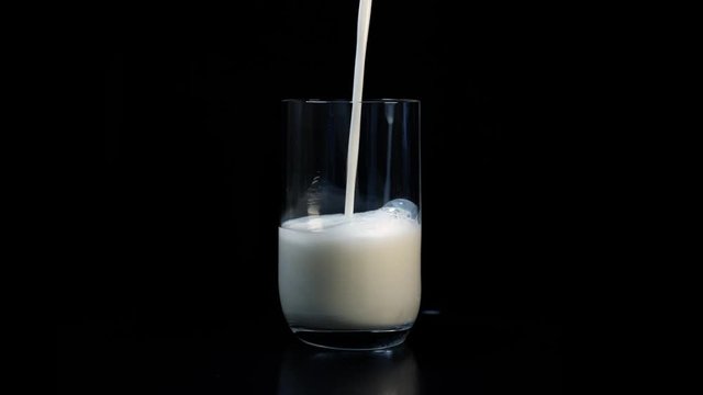 Pouring Fresh Milk Into A Glass isolated against black background
