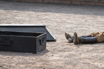 Coffin next to a dead man with his boots