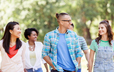 people, friendship and international concept - group of happy friends walking in park