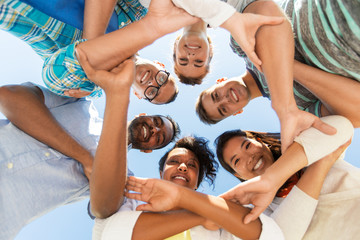people, friendship and international concept - group of happy smiling friends outdoors standing in...