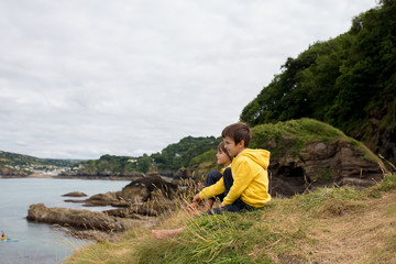 Children, enjoying quiet cloudy day on the ocean shore on the cliff, rocky beach