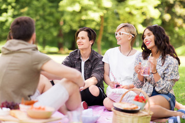 friendship and leisure concept - group of happy friends with non alcoholic drinks and food at...