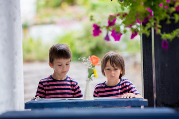 Children reading map and planning roda trip, sitting on a small blue table on the hotel porch