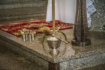 An aspergillum and altar bell at an altar prepared for mass