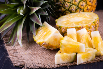 Fresh pineapple on black wood, black background.