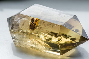 Macro shot of citrine stone on white background. Yellow, clear crystal with a dark, smokey color, smoky quartz with ornaments and rainbows in it. Powerful source of energy and healing
