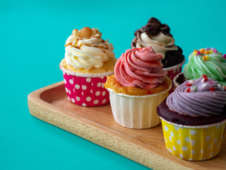 Colorful of homemade cupcake in wooden Tray on green background.