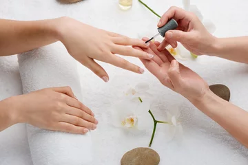  Technician applying base coat on nails. Cozy atmosphere and enjoyment of pampering. Perfect French manicure at salon. © yuriygolub