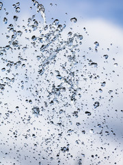 Splashing water with drops on the sky background