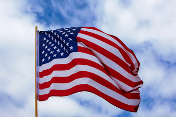 USA Flagge weht im Wind bei leicht bewölktem blauen Himmel