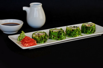 Sushi roll sushi with prawn, avocado, cream cheese, sesame. Japanese food. Healthy kale and avocado sushi roll with chopsticks.  Sushi on dark background. Set with, prawns, wasabi and ginger.