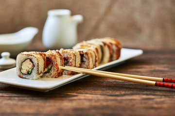 Rolls with smoked eel, calf caviar and cheese served ginger and wasabi. Delicious traditional japanese food on a  white porcelain plate  for sushi on wooden background. Sushi menu. Selective focus..