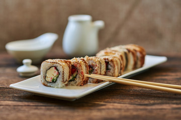 Rolls with smoked eel, calf caviar and cheese served ginger and wasabi. Delicious traditional japanese food on a  white porcelain plate  for sushi on wooden background. Sushi menu. Selective focus..