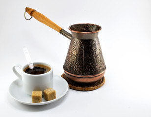 Black coffee In white porcelain Cup with sugar and copper coffee maker.