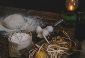 Food, cooking and baking concept. Ingredients for dough. Eggs, flour, rolling pin and eggshells on brown table. Dough preparation recipe bread, pizza or pie. Working with bakery cooking. Soft focus.