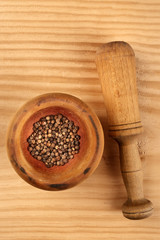 An overhead photo of black peppercorns in a mortar with a pestle, with copy space