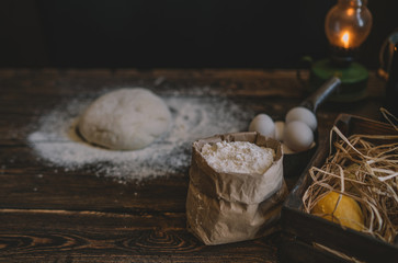 Food, cooking and baking concept. Baking bread in rustic kitchen. Dough recipe ingredients eggs, flour, milk, oil on dark vintage wooden table from above. Rural kitchen. Homemade food.
