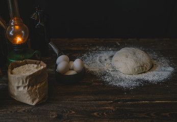 Food, cooking and baking concept. Baking bread in rustic kitchen. Dough recipe ingredients eggs, flour, milk, oil on dark vintage wooden table from above. Rural kitchen. Homemade food.