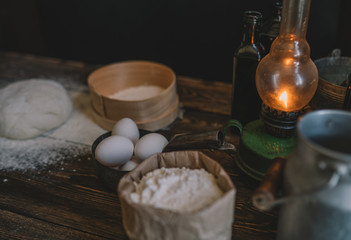 Baking ingredients placed on wooden table, ready for cooking. Concept of food preparation. Kitchen table with ingredients for cooking bread or pizza. Raw dough, flour, eggs on the wooden table.