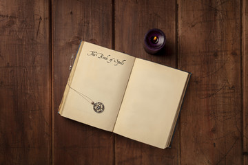 An overhead photo of a grimoire with a pentacle, a candle, and copy space