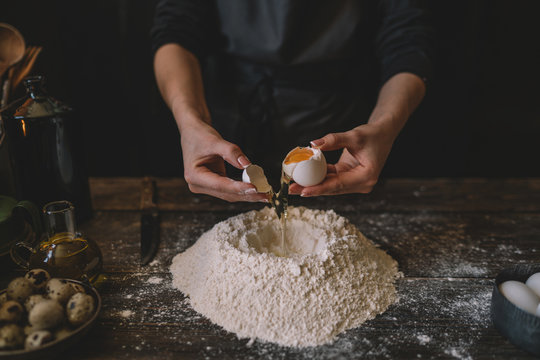Food, cooking and baking concept. Making dough by female hands at bakery. Dough background. Preparation of the dough from fresh ingredients. On a rustic background. Ingredients for homemade baking.