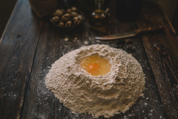 Food, cooking and baking concept. Dough on a rustic wooden background with dusting of flour. Raw dough for pizza, ingredients and kitchen accessories on dark wooden background. Rural kitchen.