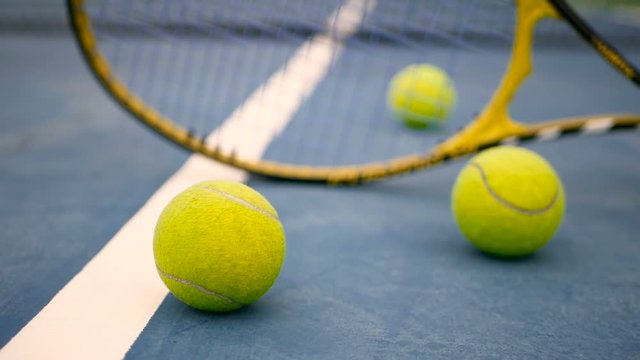 Close up of tennis equipment on the court. Sport, recreation concept. Yellow racket with a tennis ball in motion on a clay green blue court next to the white line with copy space and soft focus.