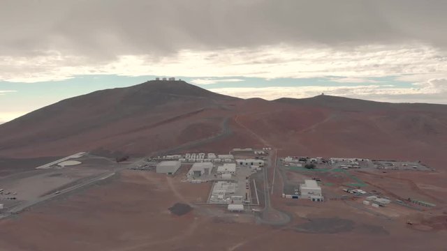 Aerial view of Very Large Telescope VLT in Atacama desert Chile. Drone flying forward during cloudy day. Science and space research facilities foreground and telescopes background at the summit.