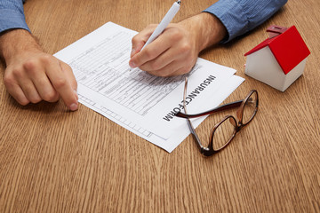 Obraz premium cropped shot of person signing insurance form at wooden table