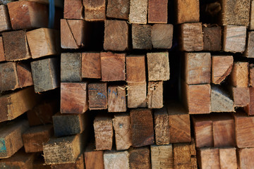 Background of the square ends of the wooden bars. Wood timber construction material for background and texture. Close up. Stack of wooden bars. Small depth of field. Pile of old wooden boards.