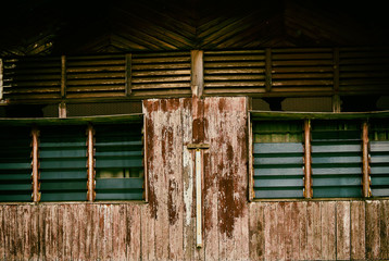 Weathered old house and windows with peeling paint and wooden plank. Abstract background and texture. Old window wooden blinds. The textured weathered wall for a background and  wallpaper.